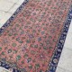 Tapis fleuri ancien sur fond rouge pastel